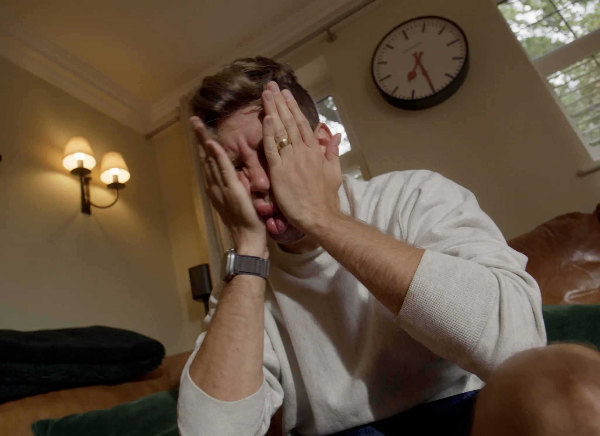 Mark G Smith slumps on the sofa with his hands over his face