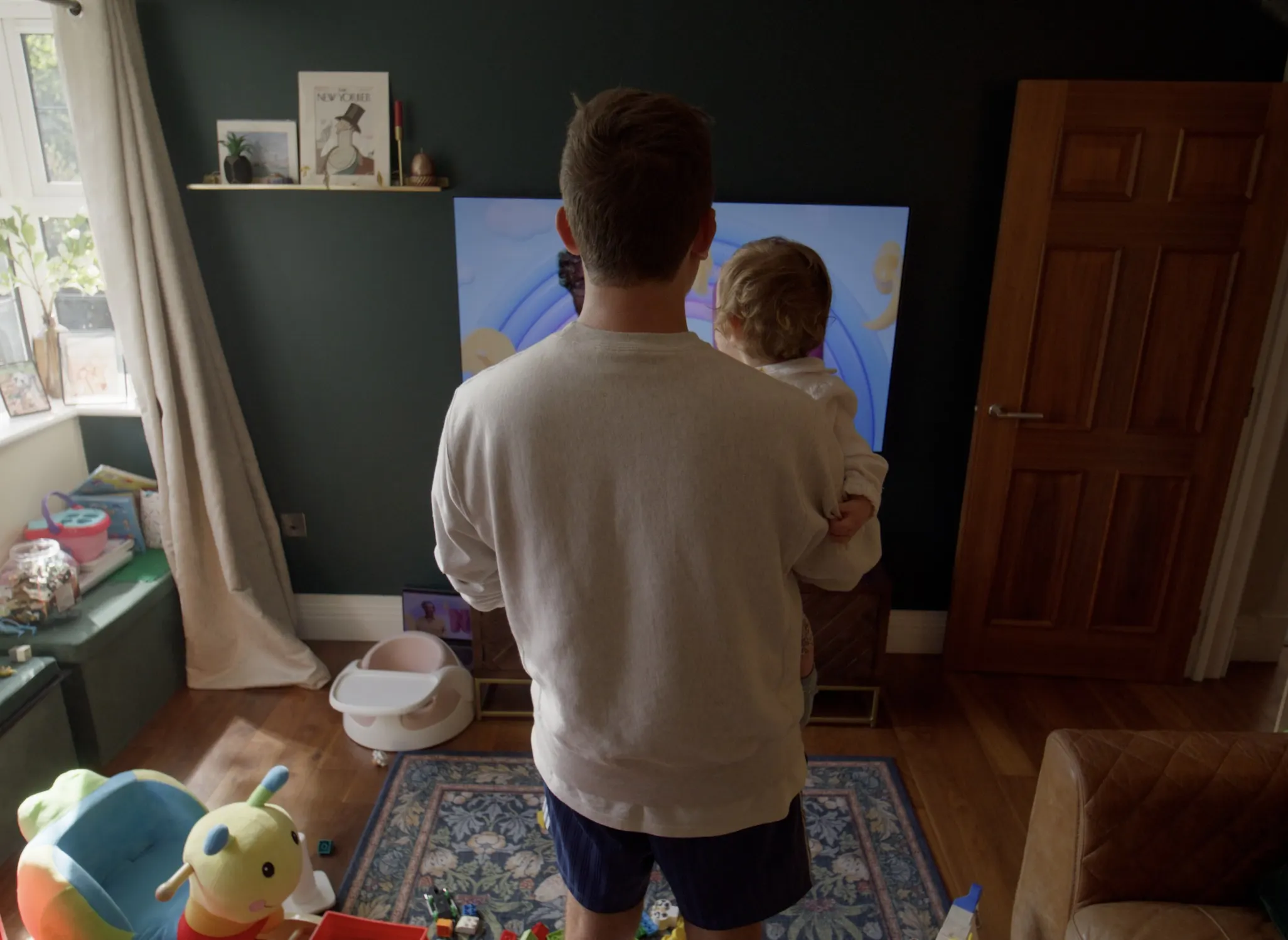 Mark G Smith holds his daughter, watching the children's channel on TV