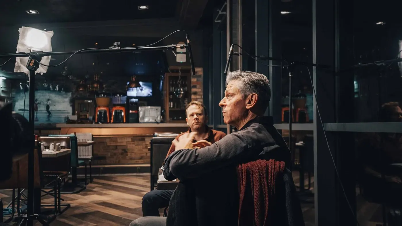 Toby Williams and David Mills seated at a table in the restaurant, waiting for the take