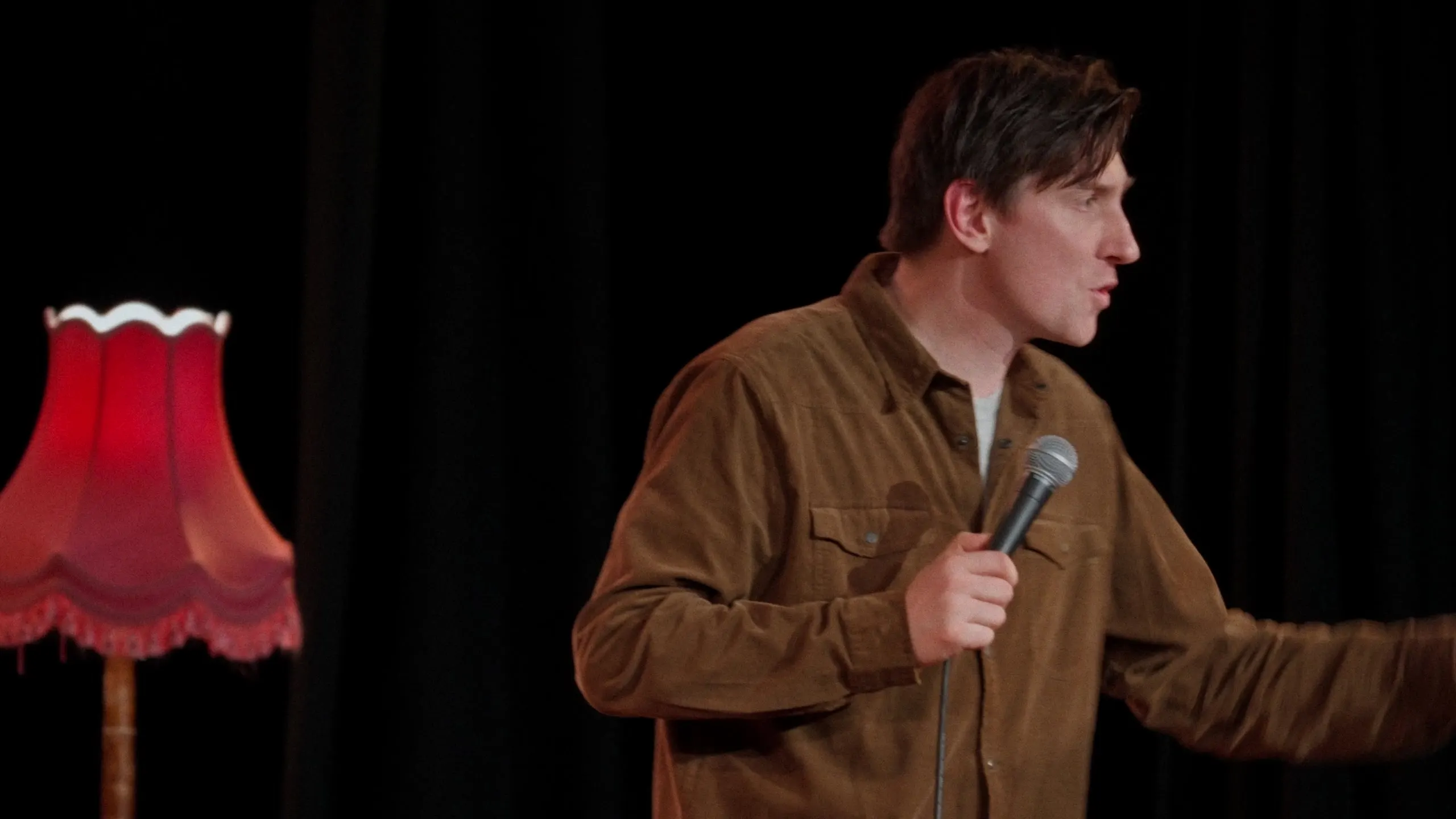 Sean McLoughlin performing beside a red fringed lamp
